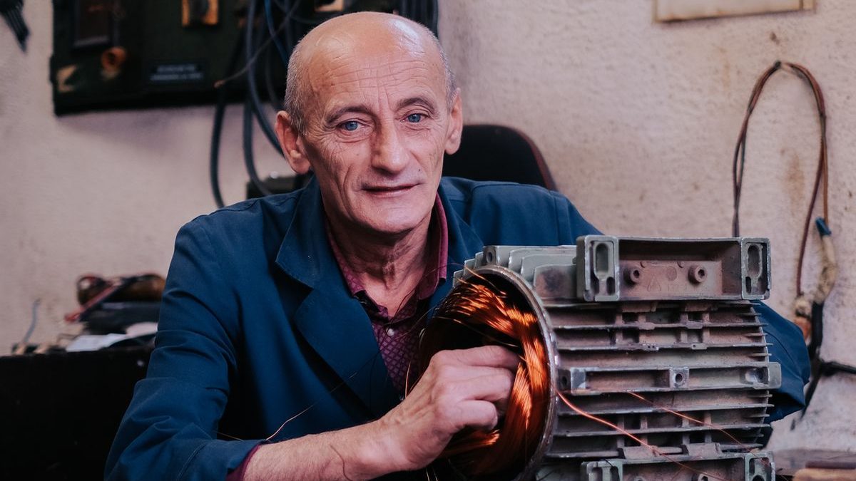 Technician servicing an electric motor armature on a workbench in a repair workshop