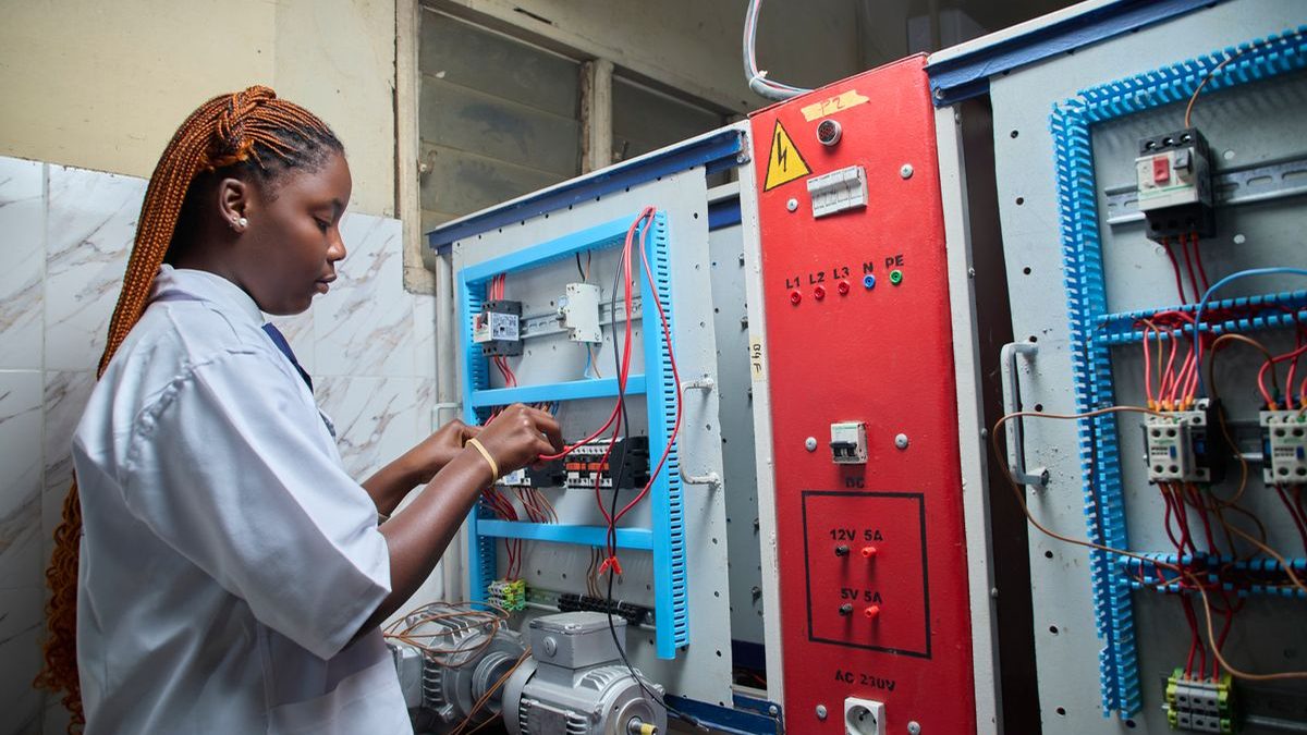 Technician measuring motor performance at an electrical test panel to verify efficiency
